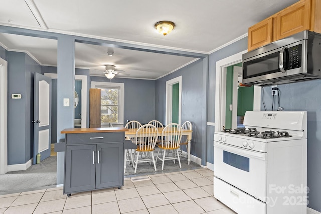 kitchen with ceiling fan, gray cabinetry, ornamental molding, white gas range, and light colored carpet