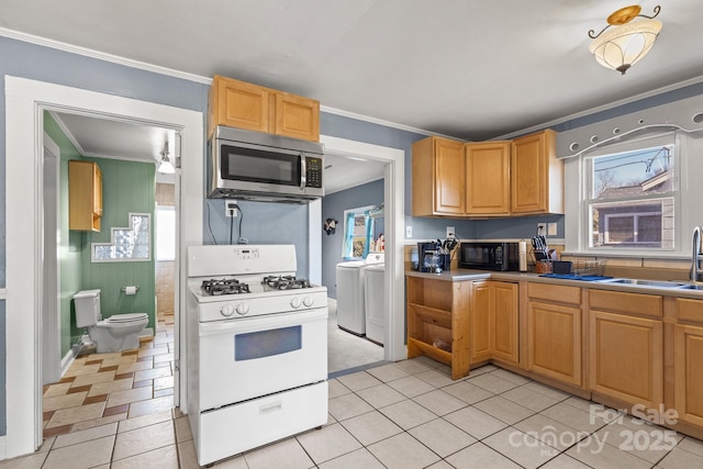 kitchen featuring plenty of natural light, white range with gas cooktop, separate washer and dryer, and sink