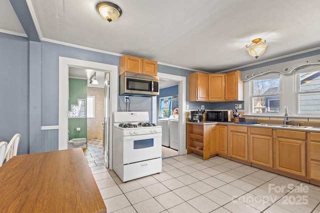 kitchen with washer and dryer, white gas range, sink, light tile patterned floors, and crown molding