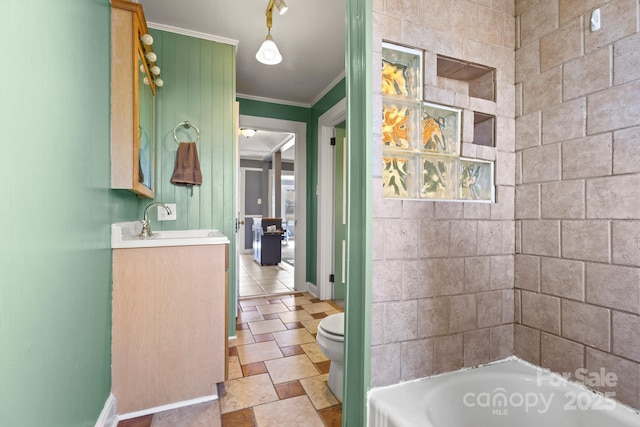 bathroom with vanity, a tub to relax in, crown molding, and toilet