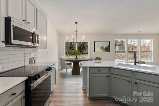 kitchen with black electric range oven, sink, backsplash, a notable chandelier, and a textured ceiling