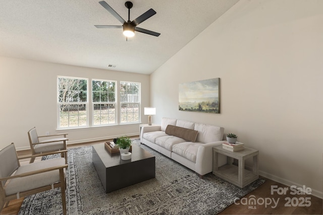 living room featuring dark wood-type flooring, ceiling fan, lofted ceiling, and a textured ceiling