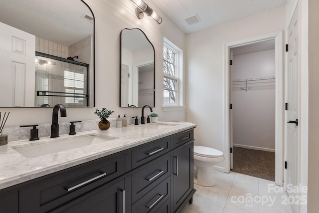 bathroom with tile patterned flooring, vanity, toilet, and walk in shower