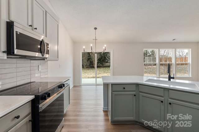 kitchen featuring sink, an inviting chandelier, a textured ceiling, light wood-type flooring, and black range with electric stovetop