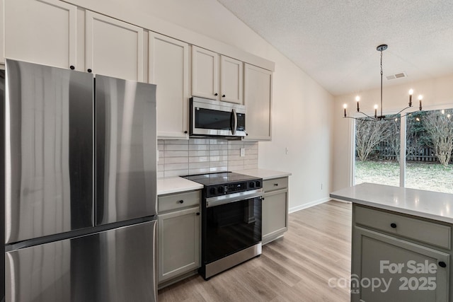 kitchen featuring tasteful backsplash, appliances with stainless steel finishes, decorative light fixtures, and gray cabinetry