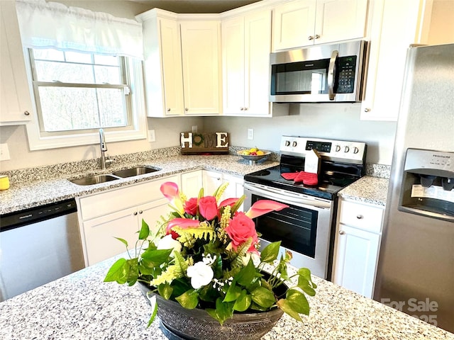 kitchen featuring sink, stainless steel appliances, white cabinets, and light stone countertops