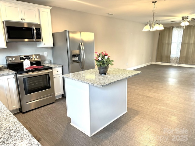 kitchen with light stone counters, decorative light fixtures, hardwood / wood-style flooring, stainless steel appliances, and white cabinets