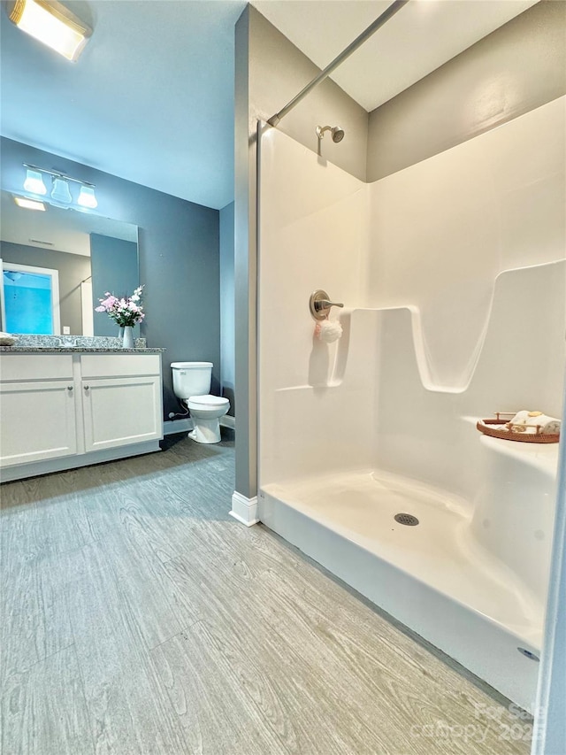 bathroom featuring hardwood / wood-style flooring, a shower, vanity, and toilet