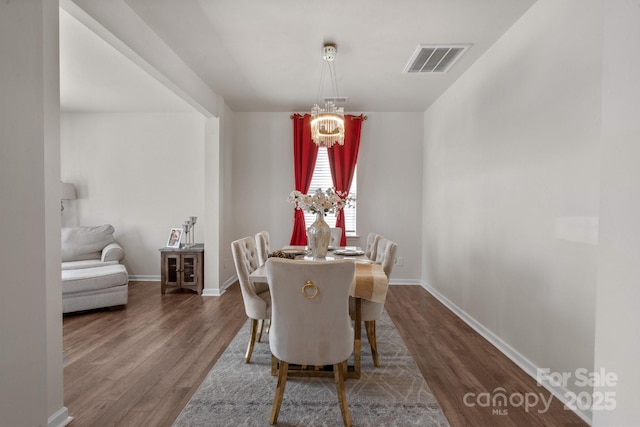 dining space featuring an inviting chandelier and dark hardwood / wood-style flooring