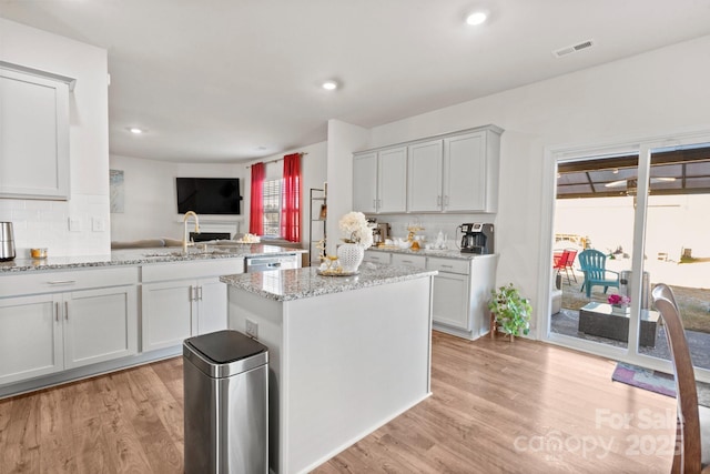 kitchen with light stone counters, sink, light hardwood / wood-style floors, and a kitchen island