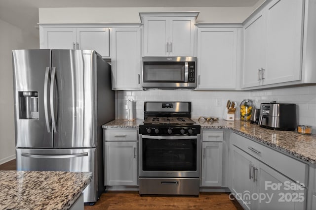 kitchen featuring backsplash, light stone countertops, white cabinets, and appliances with stainless steel finishes