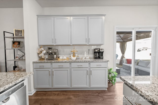 bar featuring light stone counters, dark wood-type flooring, stainless steel dishwasher, and white cabinets