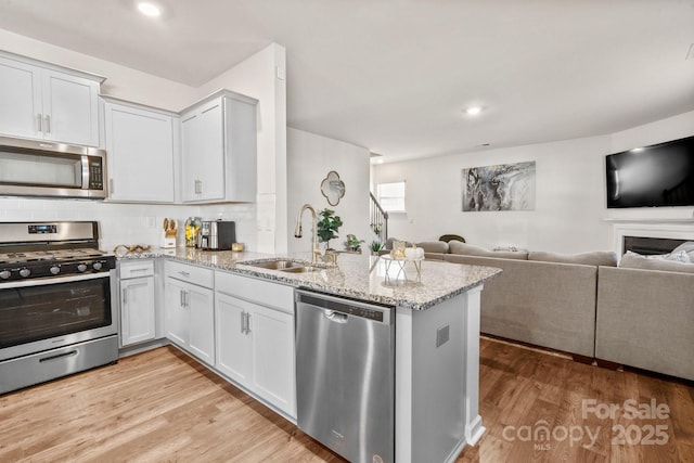 kitchen with appliances with stainless steel finishes, sink, white cabinets, and kitchen peninsula