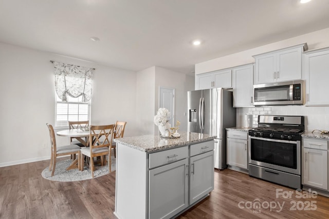 kitchen with stainless steel appliances, tasteful backsplash, a center island, and dark hardwood / wood-style floors