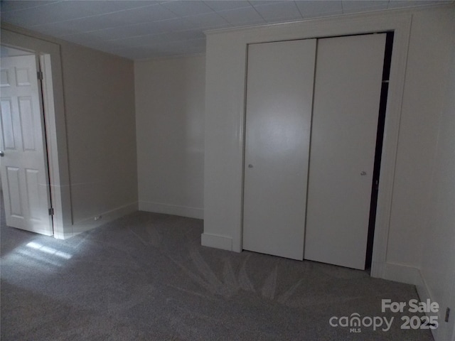 unfurnished bedroom featuring dark colored carpet and a closet