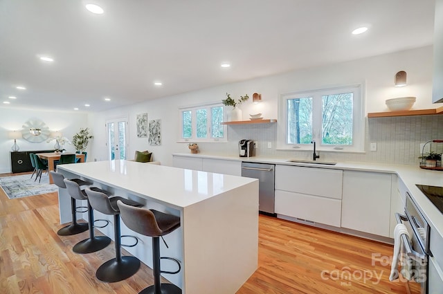 kitchen featuring a kitchen island, a breakfast bar, sink, white cabinets, and stainless steel appliances