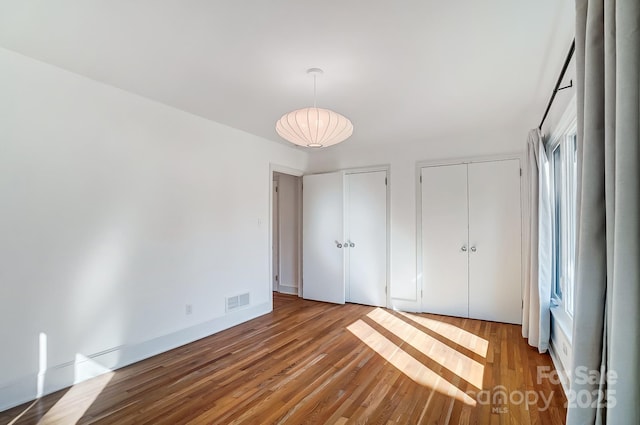 unfurnished bedroom with hardwood / wood-style flooring and two closets