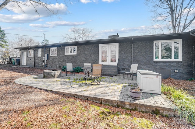 back of property with french doors, an outdoor fire pit, and a patio