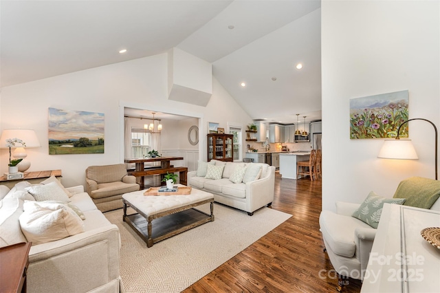 living room featuring wood-type flooring, high vaulted ceiling, and a notable chandelier