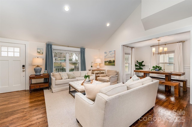 living room featuring dark wood-type flooring, a chandelier, and high vaulted ceiling