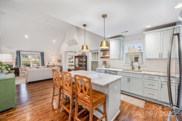 kitchen with sink, a breakfast bar area, light stone counters, pendant lighting, and white cabinets