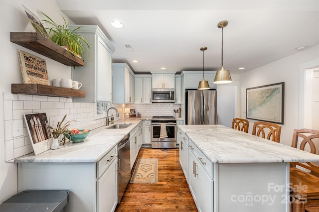 kitchen featuring pendant lighting, sink, appliances with stainless steel finishes, backsplash, and a kitchen breakfast bar