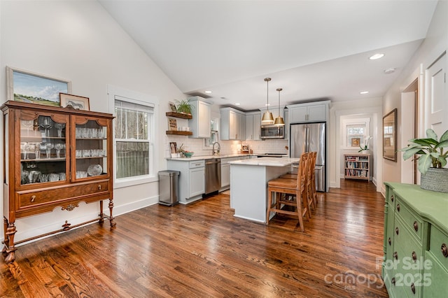 kitchen featuring lofted ceiling, a breakfast bar area, a center island, hanging light fixtures, and appliances with stainless steel finishes