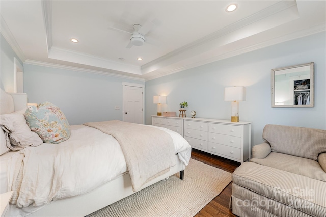 bedroom featuring crown molding, dark hardwood / wood-style floors, a raised ceiling, and ceiling fan