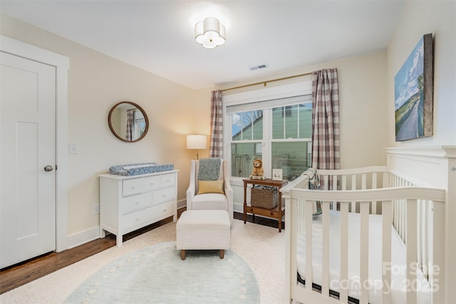 bedroom with hardwood / wood-style flooring and a nursery area