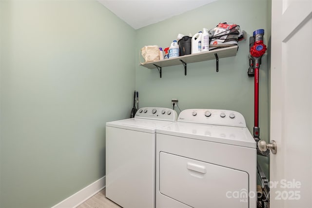 laundry area with washing machine and clothes dryer and light wood-type flooring