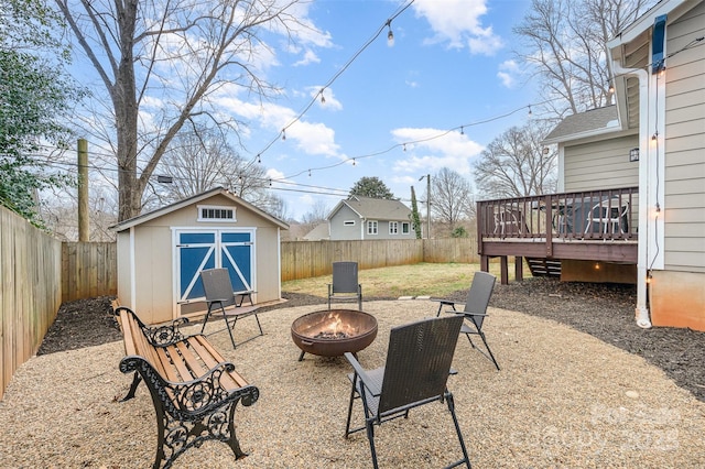 view of yard featuring an outdoor fire pit, a deck, and a storage unit