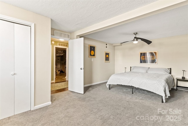 carpeted bedroom with ceiling fan, a closet, and a textured ceiling