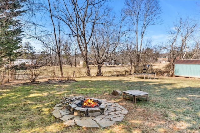 view of yard featuring a trampoline, a storage shed, and an outdoor fire pit