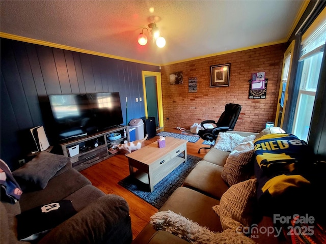 living room with crown molding, brick wall, hardwood / wood-style floors, and a textured ceiling