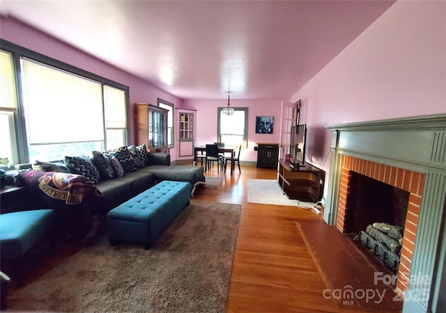 living room featuring wood-type flooring and a brick fireplace