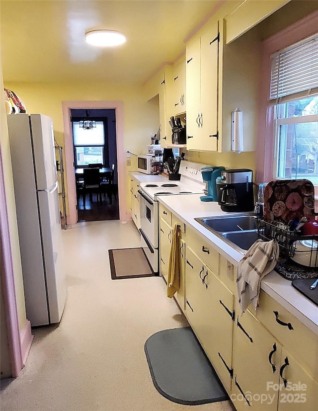 kitchen featuring sink, white appliances, and cream cabinetry