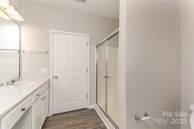 full bath featuring a shower stall, vanity, visible vents, toilet, and wood finished floors