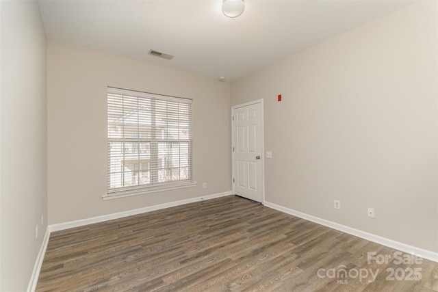 spare room with visible vents, baseboards, and wood finished floors