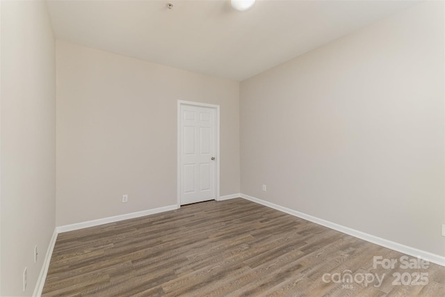 spare room with baseboards and wood finished floors