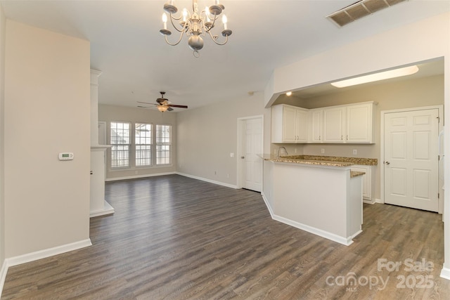 kitchen with ceiling fan with notable chandelier, dark wood finished floors, visible vents, white cabinets, and baseboards