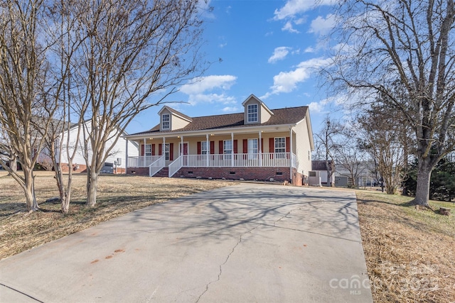 cape cod home featuring covered porch and a front lawn