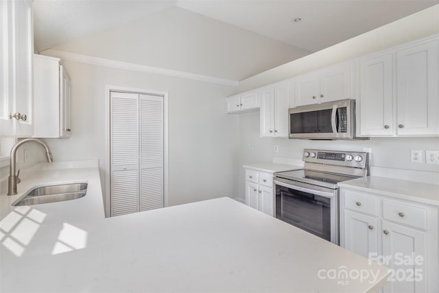 kitchen with lofted ceiling, appliances with stainless steel finishes, sink, and white cabinets