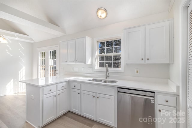 kitchen featuring sink, dishwasher, white cabinets, vaulted ceiling, and kitchen peninsula