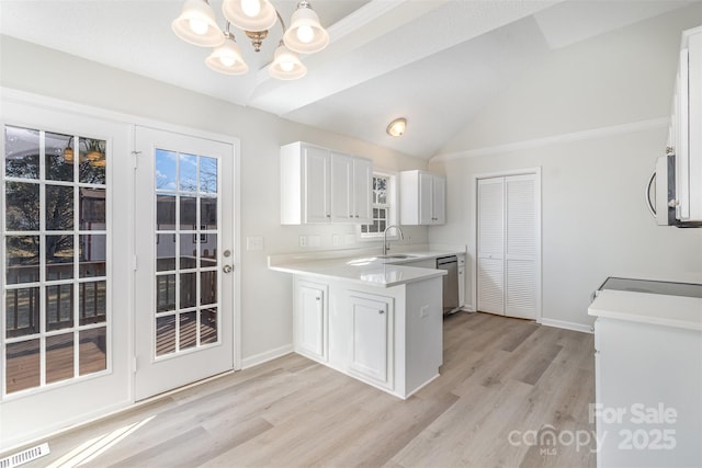 kitchen with sink, hanging light fixtures, stainless steel appliances, light hardwood / wood-style floors, and white cabinets