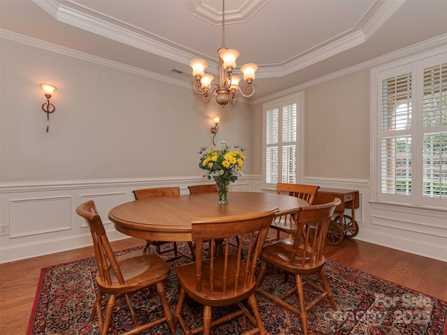 dining area with crown molding, a raised ceiling, and hardwood / wood-style flooring