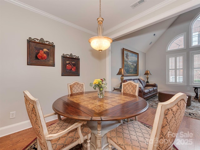 dining space featuring crown molding, wood-type flooring, and vaulted ceiling