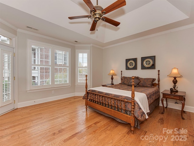 bedroom featuring ceiling fan, a raised ceiling, and light wood-type flooring