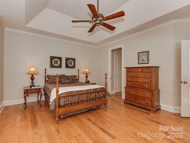 bedroom featuring crown molding, a tray ceiling, ceiling fan, and light wood-type flooring