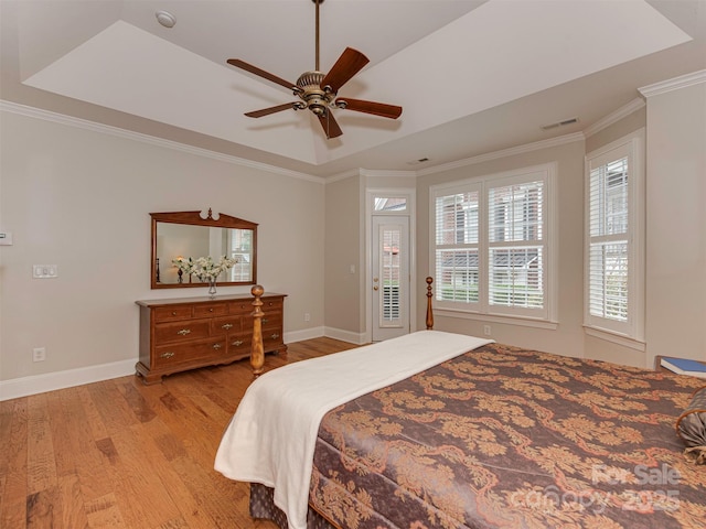 bedroom with crown molding, a raised ceiling, ceiling fan, and light wood-type flooring