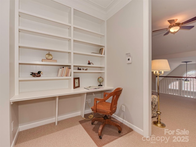 carpeted office space with built in shelves, built in desk, ornamental molding, and ceiling fan